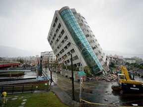 Rescue workers block off the area outside a building which tilted to one side after its foundation collapsed in Hualien after a quake rocked eastern Taiwan early on February 7, 2018.