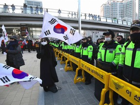 An anti-North Korea protester waves a South Korean flag in front of a police line during a rally against planned North Korea's musical concert near the Gangneung Art Centre in Gangneung, the host city of the ice venues for the Pyeongchang Winter Olympic Games, on February 8, 2018