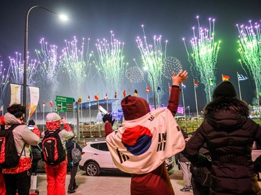People with a South Korean flag waves as fireworks get off outside the stadium during the opening ceremony of the Pyeongchang 2018 Winter Olympic Games at the Pyeongchang Stadium on February 9, 2018.