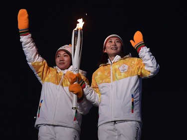 Unified Korea torchbearers, North Korean Jong Su Hyon and South Korean Park Jong-ah hold the Olympic Flame before the lighting of the cauldron during the opening ceremony of the Pyeongchang 2018 Winter Olympic Games at the Pyeongchang Stadium on February 9, 2018.