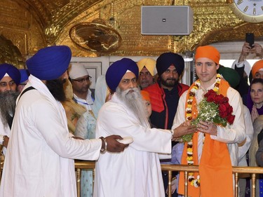 Canadian Prime Minister Justin Trudeau, in orange headgear, receives a bouquet from the Sikh priest during his visit to Golden Temple, in Amritsar, India, Wednesday, Feb. 21, 2018. Trudeau is on a seven-day visit to India.