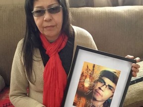 Micheline Knapaysweet holds a picture of her son Joey Knapaysweet while a wearing a red scarf her son‚Äôs favourite colour in this handout image. The grieving mother of a young Indigenous man killed by police in northern Ontario spoke out Thursday, saying the family remains in shock and still doesn't understand why her son died.