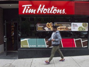 A pedestrian walk past a Tim Hortons coffee shop in downtown Toronto on June 29, 2016. Tim Hortons says it is working with an external vendor to address a virus causing intermittent cash register outages.