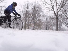 A woman steers her bicycle down a snowy Montreal street during a snowfall Tuesday, December 12, 2017. Vehicles can't turn right on red on the Island of Montreal but if the Plante administration has its way, cyclists would get the green light to do so.