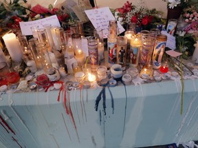 People pay homage with flowers and candles for the 17 deceased students and faculty from the Wednesday shooting at Marjory Stoneman Douglas High School, in Parkland, Fla., Friday, Feb. 16, 2018. Nikolas Cruz, a former student, was charged with 17 counts of premeditated murder on Thursday.