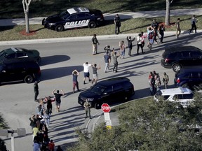 n this Feb. 14, 2018 file photo, students hold their hands in the air as they are evacuated by police from Marjory Stoneman Douglas High School in Parkland, Fla., after a shooter opened fire on the campus.