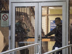 Police stand in the front doors of the courthouse in Maniwaki, Que. after two people were injured in a shooting there, on Wednesday, Jan. 31, 2018.