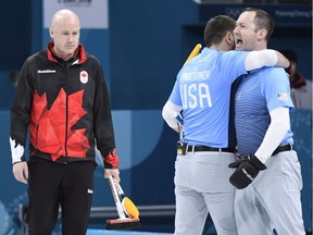 Canada skip Kevin Koe looks on as members of Team USA celebrate winning the match during men's semifinal curling action against the USA at the 2018 Winter Olympics in Gangneung, South Korea, Thursday, Feb. 22, 2018.