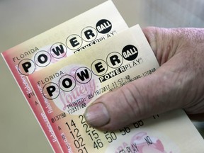 In this Aug. 18, 2017, file photo, a customer shows his purchased Powerball tickets in Hialeah, Fla.