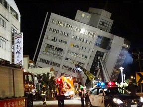 Rescuers are seen entering a building that collapsed onto its side from an early morning 6.4 magnitude earthquake in Hualien County, eastern Taiwan, Wednesday, Feb. 7 2018.  Rescue workers are searching for any survivors trapped inside the building.