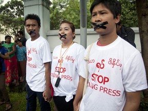 FILE - In this July 12, 2014, file photo, Myanmar journalist Thet Oo Maung, known as Wa Lone, right, stands with other journalists with their mouths taped, symbolizing the government's crackdown on media, in Yangon, Myanmar. Under Aung San Suu Kyi, Myanmar has aggressively pursued legal charges against dozens of journalists, along with other attempts to suppress and discredit the media.