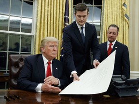 In this Jan. 20, 2017 file photo, White House Staff Secretary Rob Porter, center, hands President Donald Trump a confirmation order as Reince Priebus, right, watches.