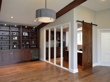 Transparent glass windows separate the home office with the family room so that the homeowners can still engage with their children while working. Similar to the library, the office opens with a sliding barn door.