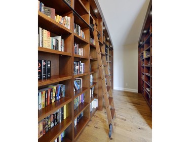 A sliding ladder was added to the library so that the family can reach books on the top shelves. There are shelves on both sides of the room holding hundreds of books.