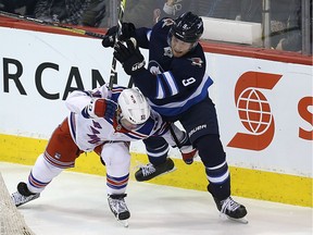 Winnipeg Jets centre Andrew Copp (right) and New York Rangers centre David Desharnais get tangled up in pursuit of a loose puck in Winnipeg on Sun., Feb. 11, 2018.