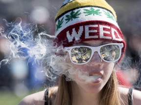 A woman exhales while smoking a joint during the annual 420 marijuana rally on Parliament Hill on Wednesday, April 20, 2016 in Ottawa