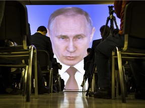 Journalists watch as Russian President Vladimir Putin gives his annual state of the nation address in Moscow on March 1.