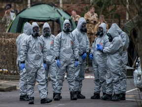 Military personnel wearing protective suits remove a police car and other vehicles from a public car park as they continue investigations into the poisoning of Sergei Skripal on March 11, 2018 in Salisbury, England.