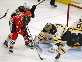 Anton Khudobin #35 of the Boston Bruins stops a shot by Nick Schmaltz #8 of the Chicago Blackhawks as Matt Grzelcyk #48 applies pressure at the United Center on March 11, 2018 in Chicago, Illinois. The Blackhawks defeated the Bruins 3-1.