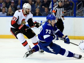 Adam Erne #73 of the Tampa Bay Lightning and Ben Harpur #67 of the Ottawa Senators fight for the puck during a game  at Amalie Arena on March 13, 2018 in Tampa, Florida.