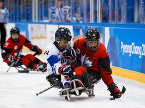 Ottawa's Ben Delaney battles for the puck with Seung Hwan Jung of Korea in the para ice hockey semifinal game at Pyeongchang on Thursday.