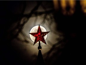 The full moon rises behind one of the Kremlin ruby stars in Moscow.