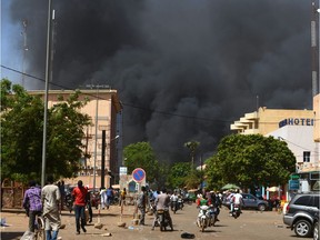 People watch as black smoke rises as the capital of Burkina Faso came under multiple attacks on March 2, 2018, targeting the French embassy, the French cultural centre and the country's military headquarters. Witnesses said five armed men got out of a car and opened fire on passersby before heading towards the embassy, in the centre of the city. Other witnesses said there was an explosion near the headquarters of the Burkinabe armed forces and the French cultural centre, which are located about a kilometre (half a mile) from the site of the first attack.