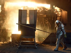 A steelworker checks the temperature of molten metal.