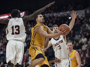 Ryerson's Manny Diressa drives to the basket between Carleton's Munis Tutu, left, and Cam Smythe during the second half.