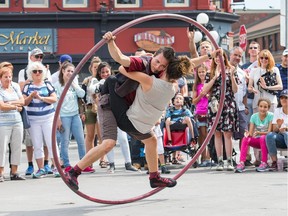 Busker Paul Perreault convinces volunteer Maude Lavallee, who is visiting the city from Paris, to join him on his ring while entertaining visitors to the Byward Market.   Photo Wayne Cuddington/ Postmedia