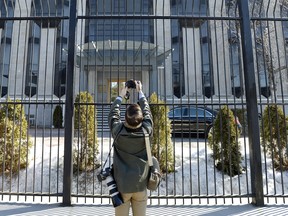 A news photographer takes pictures outside the Embassy of the Russian Federation to Canada in Ottawa on Monday, March 26, 2018.