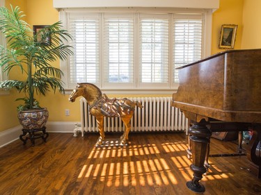 The living room of Sarah Murray's 100-year-old cottage in Rockliffe features a grand piano and a golden Asian warrior horse