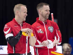 Team Canada skip Brad Gushue, right, and third Mark Nichols react as they watch Newfoundland and Labrador skip Greg Smith playing on another sheet at the Tim Hortons Brier curling championship at the Brandt Centre in Regina on Sunday, March 4, 2018.