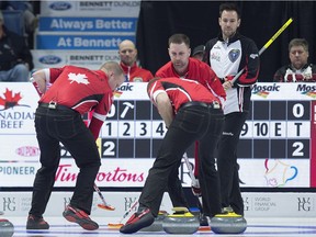 Ontario skip John Epping, right, watches as Team Canada third Mark Nichols, skip Brad Gushue and lead Geoff Walker, left to right, manoeuvre a rock in the eight-team championship round on Friday.