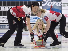 Jill Officer, left, and Dawn McEwen brush a shot by Canadian skip Jennifer Jones during a game against Switzerland earlier in the women's world curling championship at North Bay.