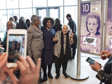 Wanda Robson, centre, sister of Viola Desmond, is surrounded by friends and family while posing next to the new $10 bank note featuring her sister following the bill's unveiling in Halifax on Thursday, March 8, 2018. Desmond is the first Canadian woman to be featured on a regularly circulating bank note.