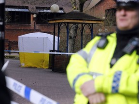 Police officer secures the area as a police tent covers the the spot in Salisbury, England, Tuesday, March 6, 2018, where former Russian spy double agent Sergei Skripal and his companion were found critically ill Sunday following exposure to an "unknown substance". 66-year old Skripal, and unidentified woman companion are being treated in hospital, after they were found unconscious on the park bench.