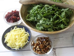 The components of an arugula salad with spicy pecan praline, dried cranberries and aged gouda.