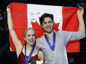 Kaitlyn Weaver and Andrew Poje of Canada celebrate on the podium after winning the bronze medal of the pairs Ice dance, at the Figure Skating World Championships in Assago, near Milan, Saturday, March 24, 2018. They won the gold medal. (AP Photo/Antonio Calanni)