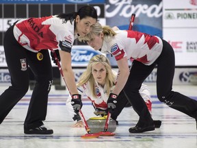 Canada skip Jennifer Jones eyes her shot while second Jill Officer (left) and lead Dawn McEwen sweep as they face Switzerland at the World Women's Curling Championship on Saturday in North Ba. (Paul Chiasson/The Canadian Press)