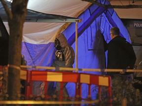 Investigators next to a police tent outside The Mill public house at the Maltings in Salisbury, England, Tuesday, March 6, 2018, near to where former Russian double agent Sergei Skripal was found critically ill. Britain's counterterrorism police took over an investigation Tuesday into the mysterious collapse of a former spy and his daughter, now fighting for their lives. The government pledged a "robust" response if suspicions of Russian state involvement are proven. Sergei Skripal and his daughter are in a critical condition after collapsing in the English city of Salisbury on Sunday.