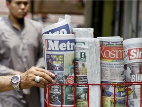 A man takes a copy of newspaper at a grocery shop in Shah Alam, Malaysia, Monday, March 26, 2018. Malaysia's government has proposed new legislation to outlaw fake news with a 10-year jail term for offenders, in a move slammed by critics as a draconian bid to crack down on dissent ahead of a general election.