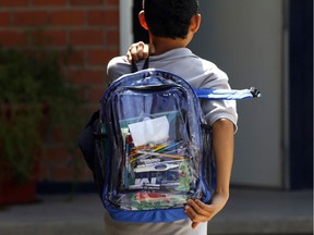 A student walks carrying a transparent backpack.