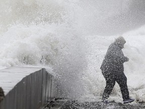 A woman gets caught by a wave as heavy seas continue to come ashore.
