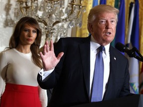 FILE - In this Friday, Oct. 6, 2017, file photo, President Donald Trump speaks during an event at the White House in Washington, as first lady Melania Trump listens. Trump's plan to combat opioid drug addiction calls for stiffer penalties for drug traffickers, including the death penalty where it's appropriate under current law. The president is scheduled to unveil his plan Monday, March 19, 2018, in New Hampshire, a state hard-hit by the crisis. He'll be accompanied by first lady Melania Trump, who has shown an interest in the issue, particularly as it pertains to children.