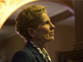 Ontario Premier Kathleen Wynne talks to a journalist in a hallway at the Ontario Legislature in Toronto on Monday, March 19, 2018.