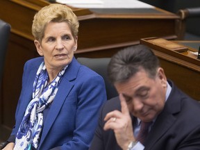 Ontario Premier Kathleen Wynne looks on next to Provincial Finance Minister Charles Sousa as she listens to Ontario Lt.-Governor Elizabeth Dowdeswell, not shown, deliver the Speech from the Throne at the Ontario Legislature, in Toronto on Monday, March 19, 2018.