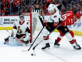 Senators netminder Mike Condon watches as defenceman Christian Wolanin battles with Red Wings winger Darren Helm for the puck near the crease during the second period of Saturday's game.