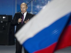 Russian President Vladimir Putin speaks in front of a Russian National flag.