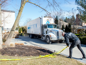 A security guard reattaches the caution tape after allowing a 'Apotex' truck to enter the driveway of the Toronto home of Barry and Honey Sherman on Monday, March 5, 2018.